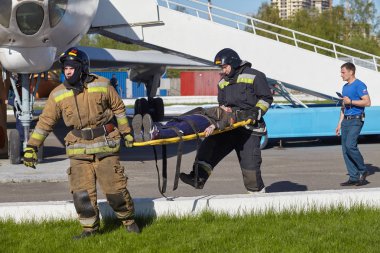 St. Petersburg, Rusya Federasyonu - 12 Mayıs 2018: yarışma / egzersizleri ilk yardım öncesi hastane aşamada. İtfaiyeciler uçakta yangın sırasında kurban sedye üzerinde yürütmek.