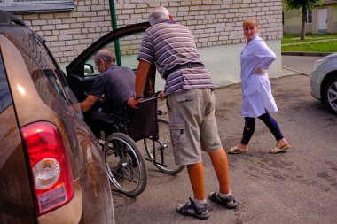 Belarus. Minsk Grodno bölge - 11 Haziran 2018: Şehir Hastanesi Acil servis, tekerlekli sandalyede bir adam. Kırık bacak sıvalı. Birlikte asistanı.