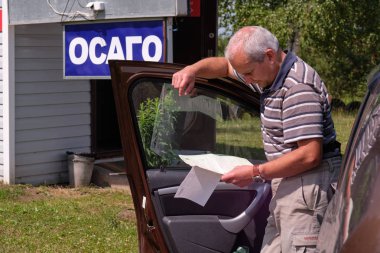 Pskov bölgesi. Rusya - 5 Temmuz 2018: Nokta-in satış yeşil araba kartları ve sigorta Ctp sınır Rusya ile. Adam sigorta belgeleri inceler.