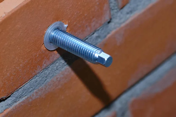 Stage of installation of a chemical anchor in a red building brick with cellular voids. Demonstration of the correctness of the actions of the builder. Close-up.