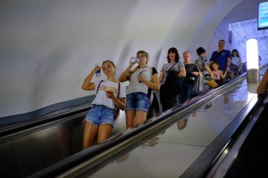 İnsanlar bir metro yürüyen merdiven üzerinde. Yapay ışık. İç metro s