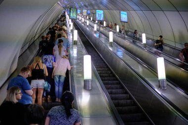 İnsanlar bir metro yürüyen merdiven üzerinde. Yapay ışık. İç metro s
