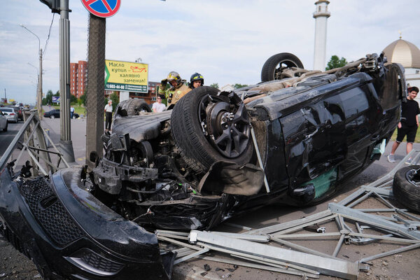 Saint Petersburg, Russia - July 21, 2020: Cherokee SUV jeep inverted after a severe road collision in the city. Firefighters eliminate gas tank explosion threat