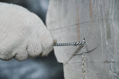Kırıntılardan ve tozdan kimyasal çapalar elde etmek için beton bir duvara kazılmış küçük deliklerin temizlenmesi. Çalışma süreci. Eldiven verin. Metal fırça