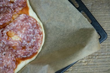 A yakın çekim hazır salam et düz ekmek fırın tepsisi ve ahşap masa pişmiş olması.