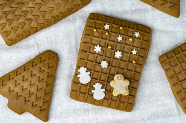 Farklı şekiller çerezleri Noel tedavi tema beyaz masa örtüsü yerleştirilir. Closeup yukarıdan izlendi. Beyaz kar taneleri, kardan adam ve Noel ağacı