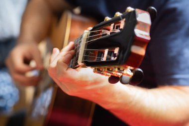 Adam akustik gitar çalıyor.