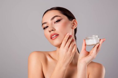 Şık ve çarpıcı genç bir bayana yakından bakın güzellik ürünü sunuyor, zarafet ve cilt bakımını vurguluyor..