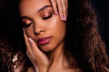 Kusursuz makyajlı, pürüzsüz ciltli, kıvırcık saçlı, dingin ve büyüleyici bir anda zarif ve güzel bir kadının yakın plan portresi..