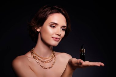 Göz kamaştırıcı model ünlünün portresi el ele tutuşuyor. Siyah arka planda izole edilmiş yeni anti-yaş serumu şişesi..