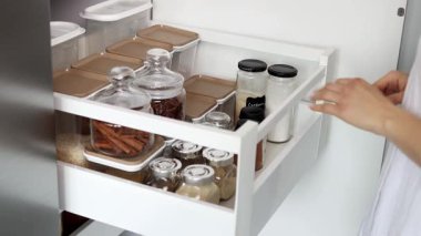 Kadın ellerinin yavaş çekimde baharatlarla bir çekmeceyi kapatması. Mutfakta baharat depoluyor. Ev rutini.