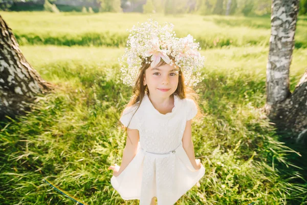 Feliz joven con una corona de flores en la cabeza y un vestido blanco sonriendo felizmente — Foto de Stock
