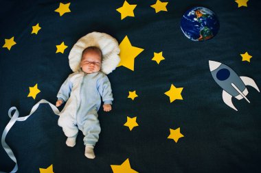 bir roket ve gezegen ile yıldızlı gökyüzü arka plan üzerinde erkek bebek uyur