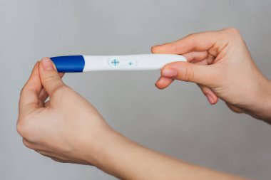 hamile bir kız elinde pozitif gebelik testi