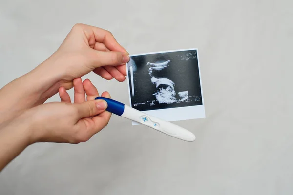Imagen de ultrasonido y prueba de embarazo positiva en las manos de una niña — Foto de Stock