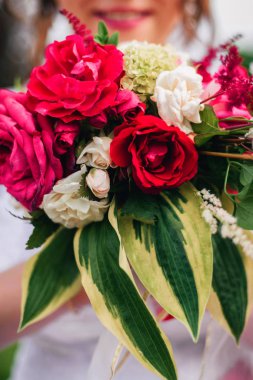 gülümseme ile mutlu gelinin elinde düğün buket kırmızı peonies ve yeşil yaprakları