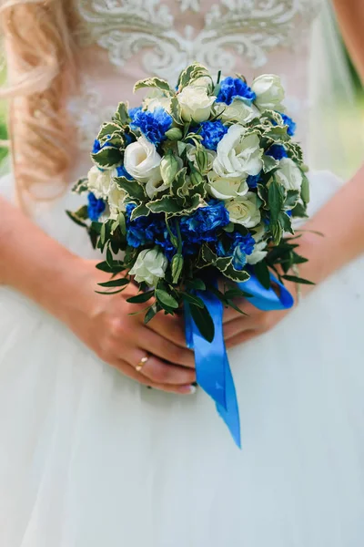 Hochzeit schöner Strauß mit weißen Rosen und blauen Blumen in den Händen der Braut mit einem Ring — Stockfoto