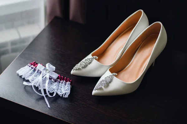 Γαμήλια παπούτσια νύφη ντυμένη στα λευκά με ασημένια σκουλαρίκια — Φωτογραφία Αρχείου