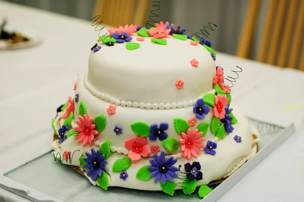 Свадебный торт с белой глазурью с красочными цветами — стоковое фото