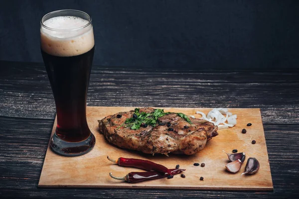 Varkensvlees met kruiderijen en een glas bier op een cutting Board — Stockfoto