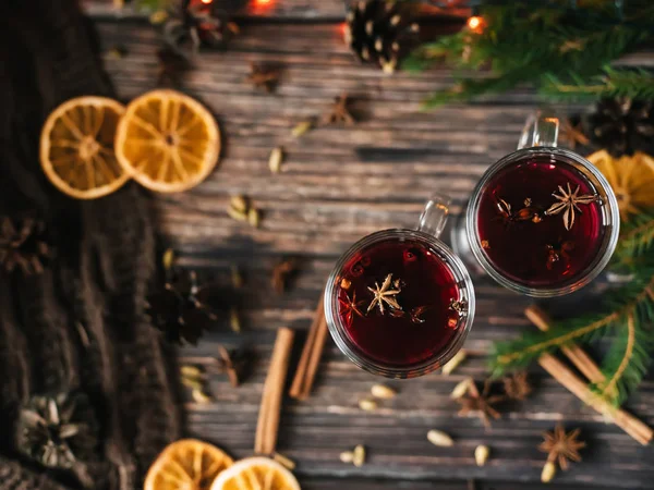 two glasses with mulled wine on a wooden table with orange, cinnamon, cardamom, anise stars. Traditional winter hot alcoholic drink