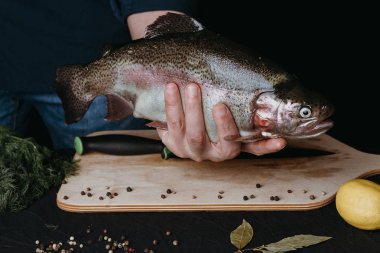 Erkek mutfak arka plan üzerinde elinde balık. Büyük taze alabalık