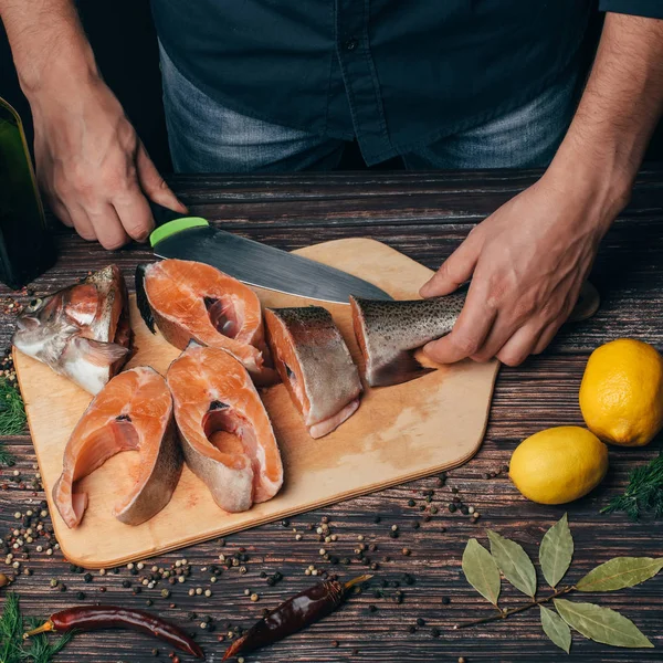 Pescado rojo fresco cortado en el tablero y las manos del chef masculino — Foto de Stock