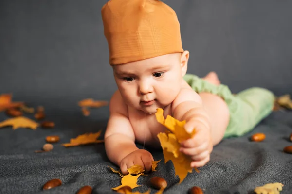 Újszülött fiú fekszik őszi háttér, juharlevél és makk — Stock Fotó