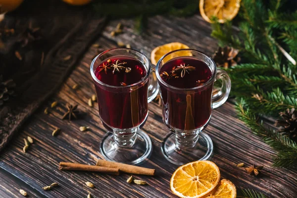 Vinho quente em copos de vidro com fatias de laranja, paus de canela e especiarias com decoração de Natal — Fotografia de Stock