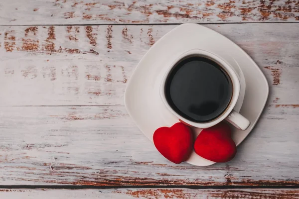 Tasse Kaffee und ein paar rote Valentinstags-Herzen auf weißem Holztisch. das Konzept der Grußkarte — Stockfoto