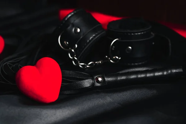 Кожаный хлыст и наручники для БДСМ секса с красными сердцами как символ Дня Святого Валентина — стоковое фото