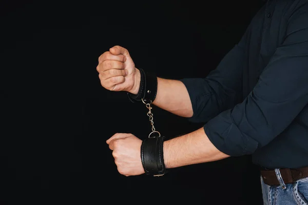 Mens hands chained in leather handcuffs on black background — Stock Photo, Image