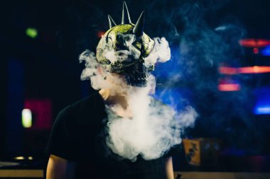 Maskeli adam bir nargile içiyor ve bir duman bulutu sağlar