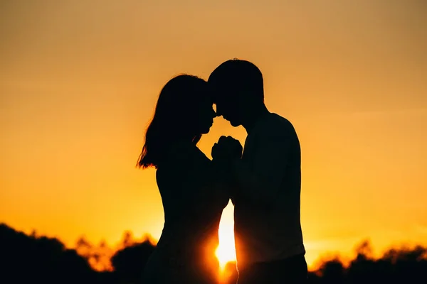 Verliebtes Paar hält Händchen bei einem orangefarbenen Sonnenuntergang im Sommer — Stockfoto