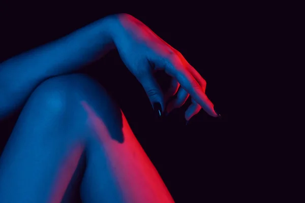 膝に女性の手がネオンの光でクローズ アップ — ストック写真