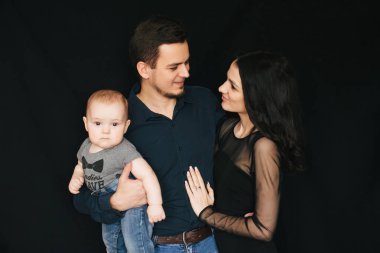 Genç siyah bir zemin üzerine beyaz aile. Mutlu baba, anne ve oğul. Seven bir çocuk tutan çift.