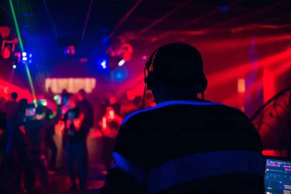 DJ змішує музику в нічному клубі з людьми, які танцюють — стокове фото