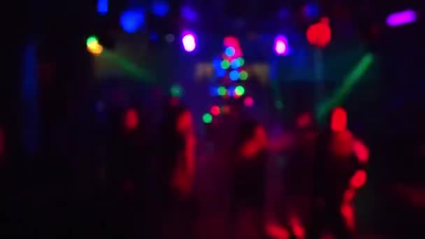 Розмиті силуети танцюючих людей в нічному клубі під кольоровим світлом прожекторів — стокове відео