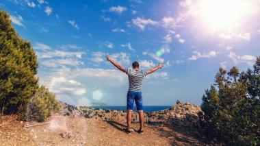 deniz ve yaz aylarında güneşli gökyüzü karşı elleri ile dağların üstüne adam gezgin geri