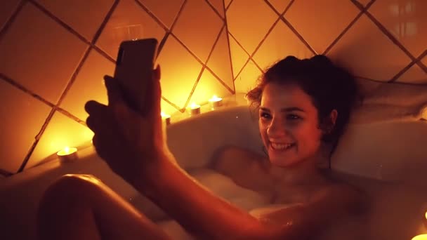 Jong meisje lacht en glimlacht terwijl het nemen van een selfie op haar smartphone in de badkamer — Stockvideo