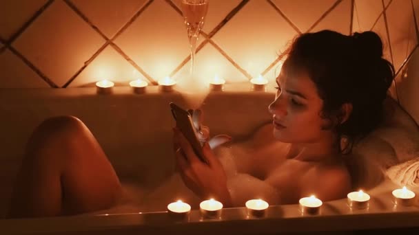 Junges Mädchen wählt auf dem Touchscreen eines Smartphones eine Nummer und telefoniert im Badezimmer liegend — Stockvideo