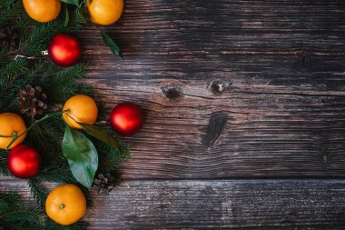 Mandalina, köknar dalları, kırmızı topları ve ahşap masa üzerinde çam kozalağı ile Noel arka plan. Geleneksel şenlikli kış dekoru