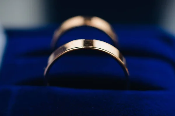 Par de anéis de casamento de ouro encontra-se em uma caixa azul — Fotografia de Stock