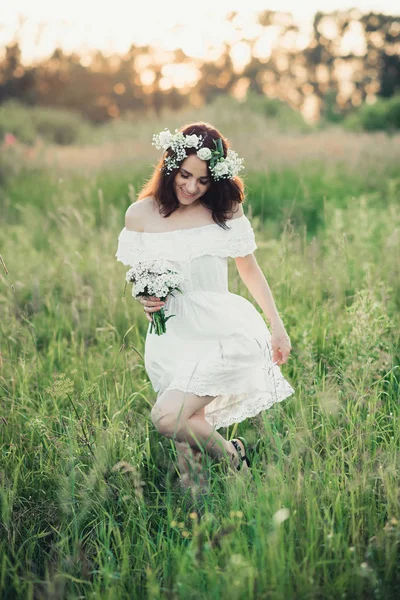 Ευτυχισμένο κορίτσι με ένα λευκό φόρεμα και ένα μπουκέτο λουλούδια χαμόγελα και χαρά — Φωτογραφία Αρχείου