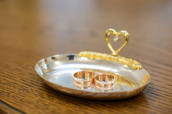 Два золотых обручальных кольца лежат на металлическом подносе — стоковое фото