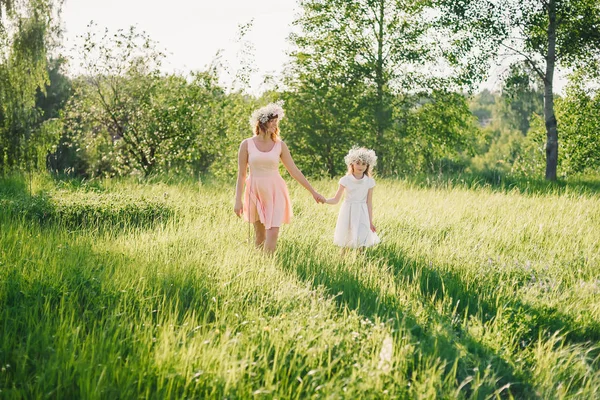 Anne ve kızı sahada günbatımı güneşli yaz gününde yürüyüş