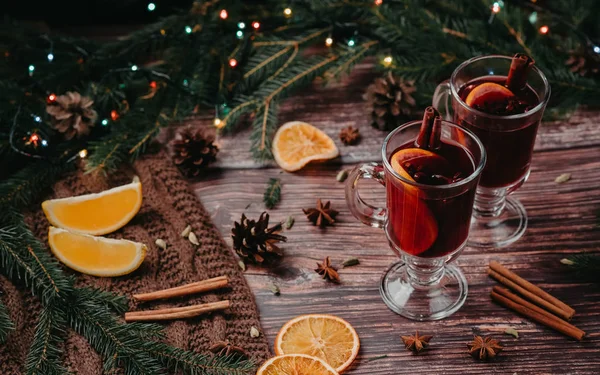 Dos copas de vino caliente navideño con especias y rodajas de naranja sobre una mesa rústica de madera — Foto de Stock