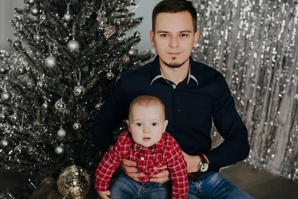クリスマス ツリーの背景で彼の父の腕の中で小さな男の子の子供 — ストック写真