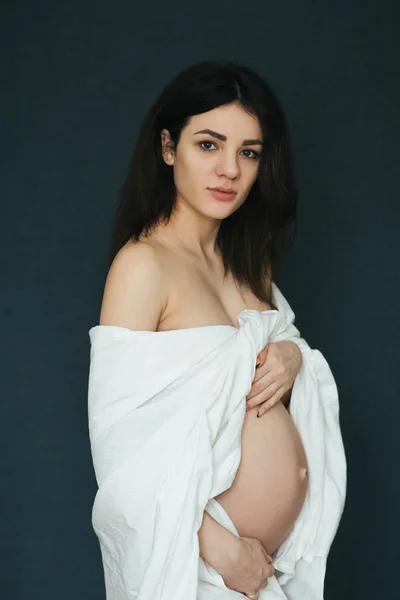 Grossesse. Attrayant jeune fille brune enceinte enveloppé dans du tissu blanc — Photo