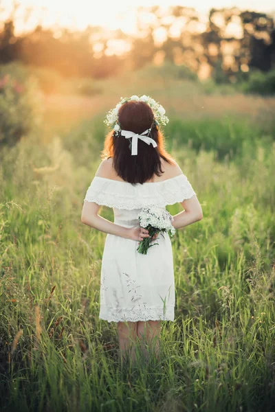 Kaukasisch glückliches Mädchen in einem weißen Kleid mit einem Blumenstrauß und einem Kranz im Sommer — Stockfoto